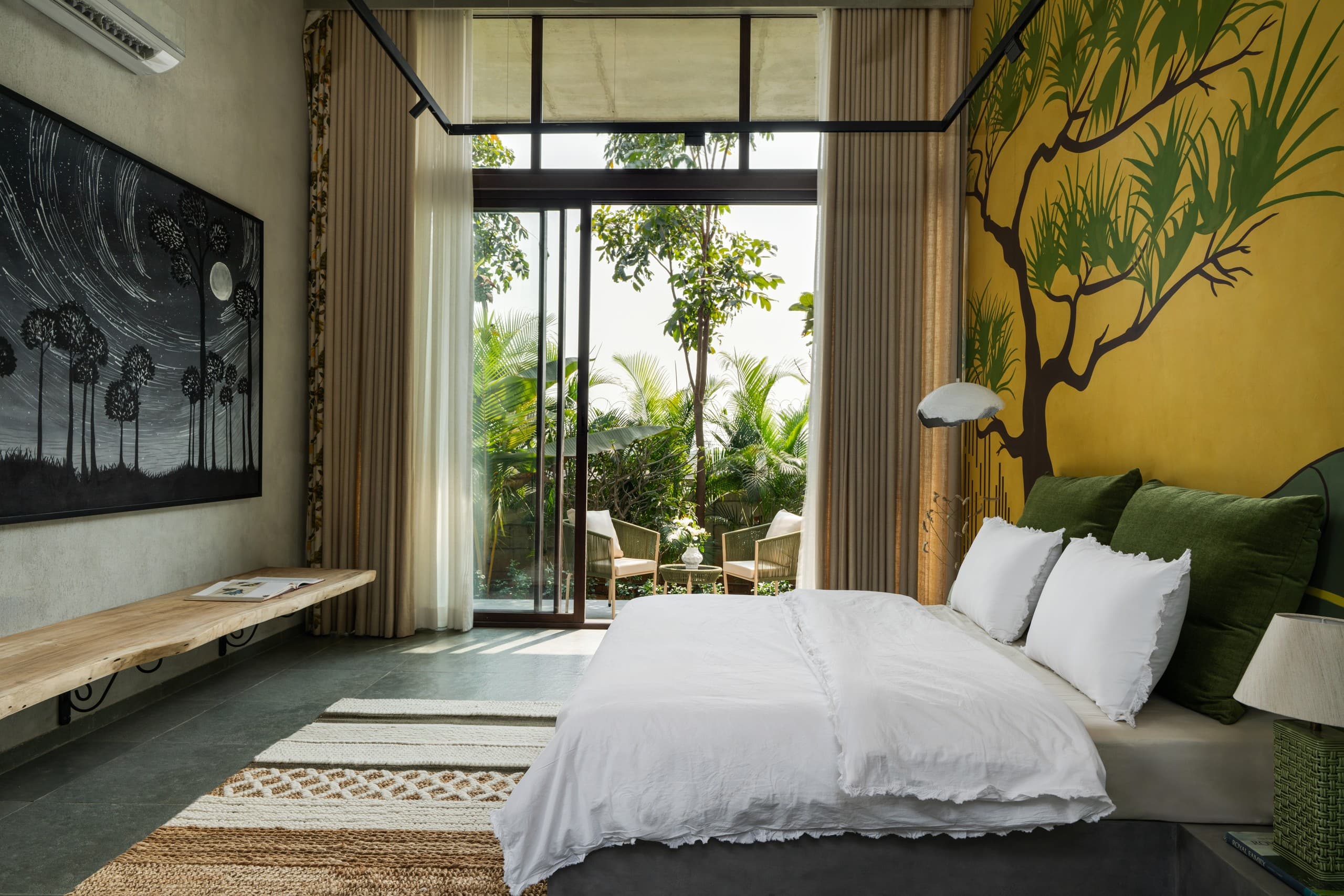 Bedroom with a dark starry canvas, timber bench and garden beyond.