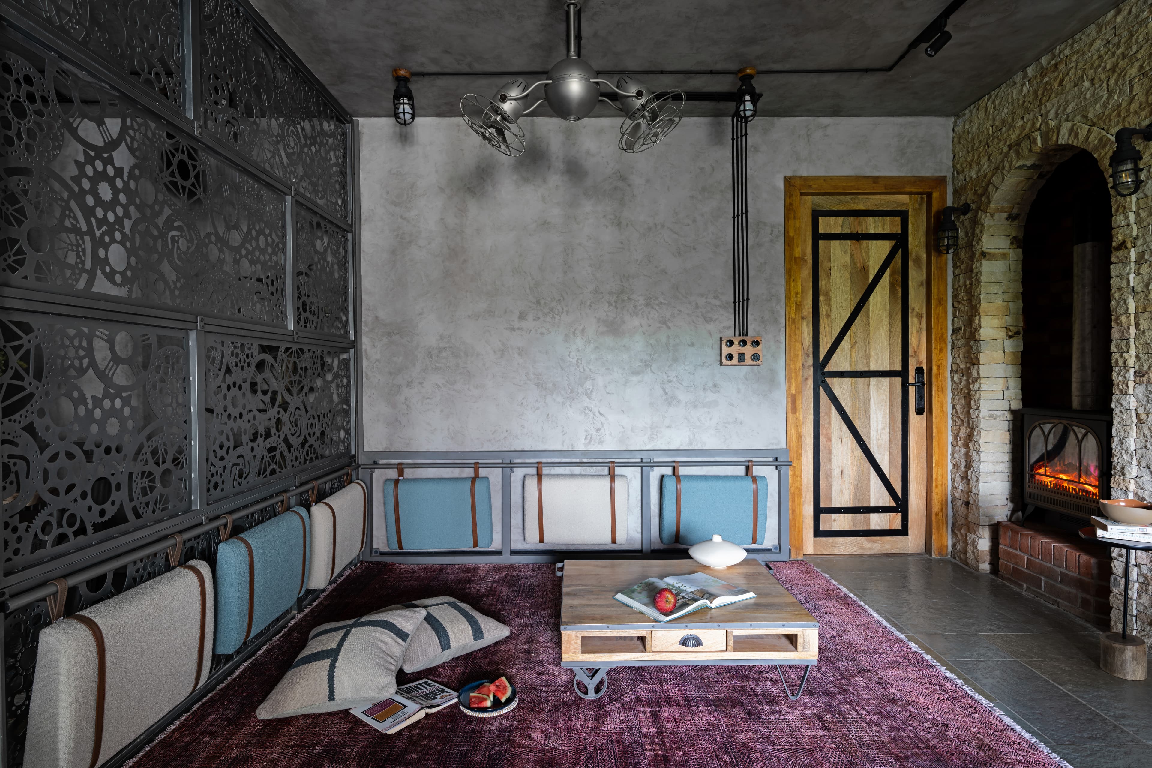 The den: blue and ivory cushions strapped in leather to a steel banquette, overdyed rug.