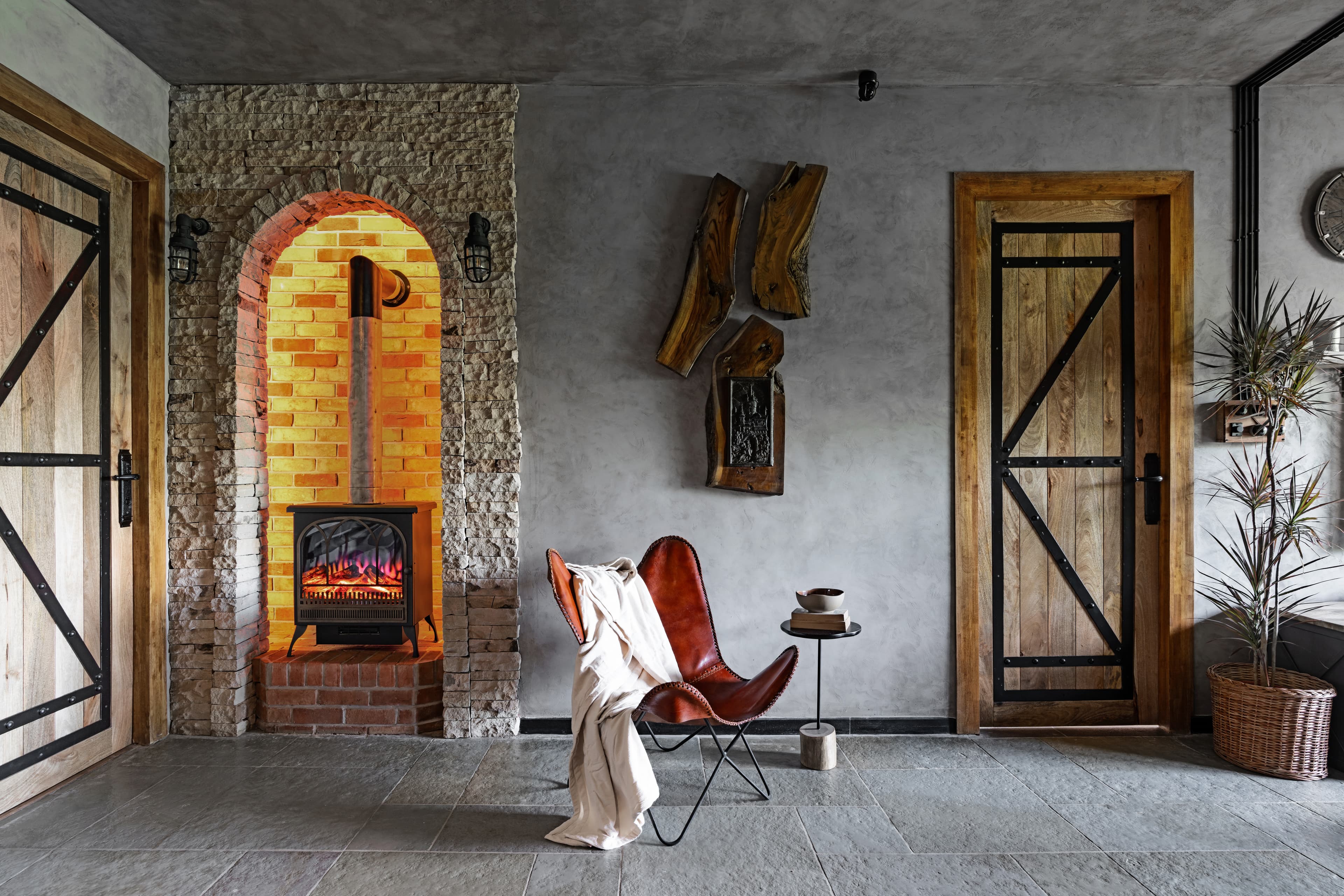 Fireplace nook: a leather butterfly chair with a cream throw beside the arched hearth.