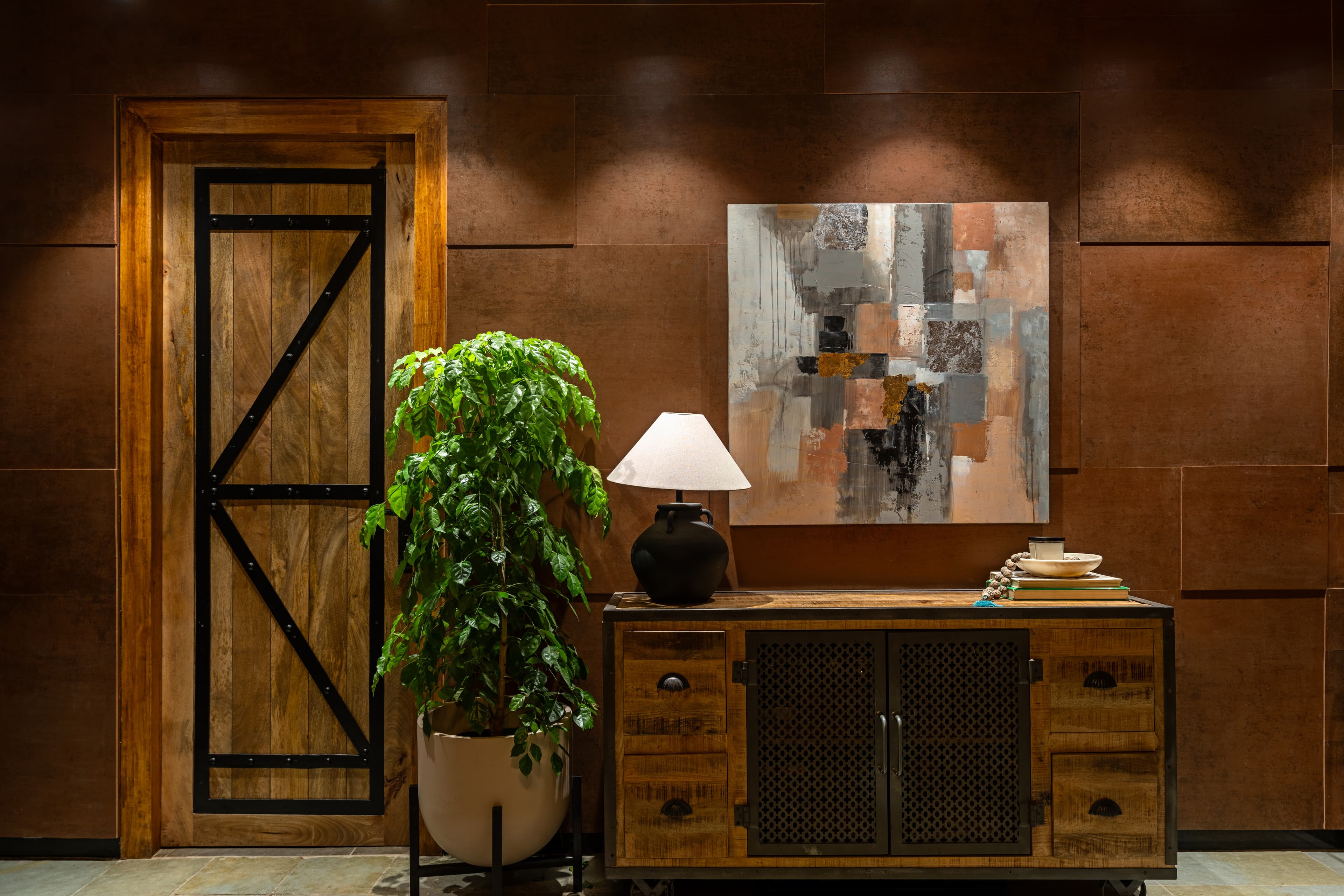Timber console beneath a painting carrying the copper wall's own colours.