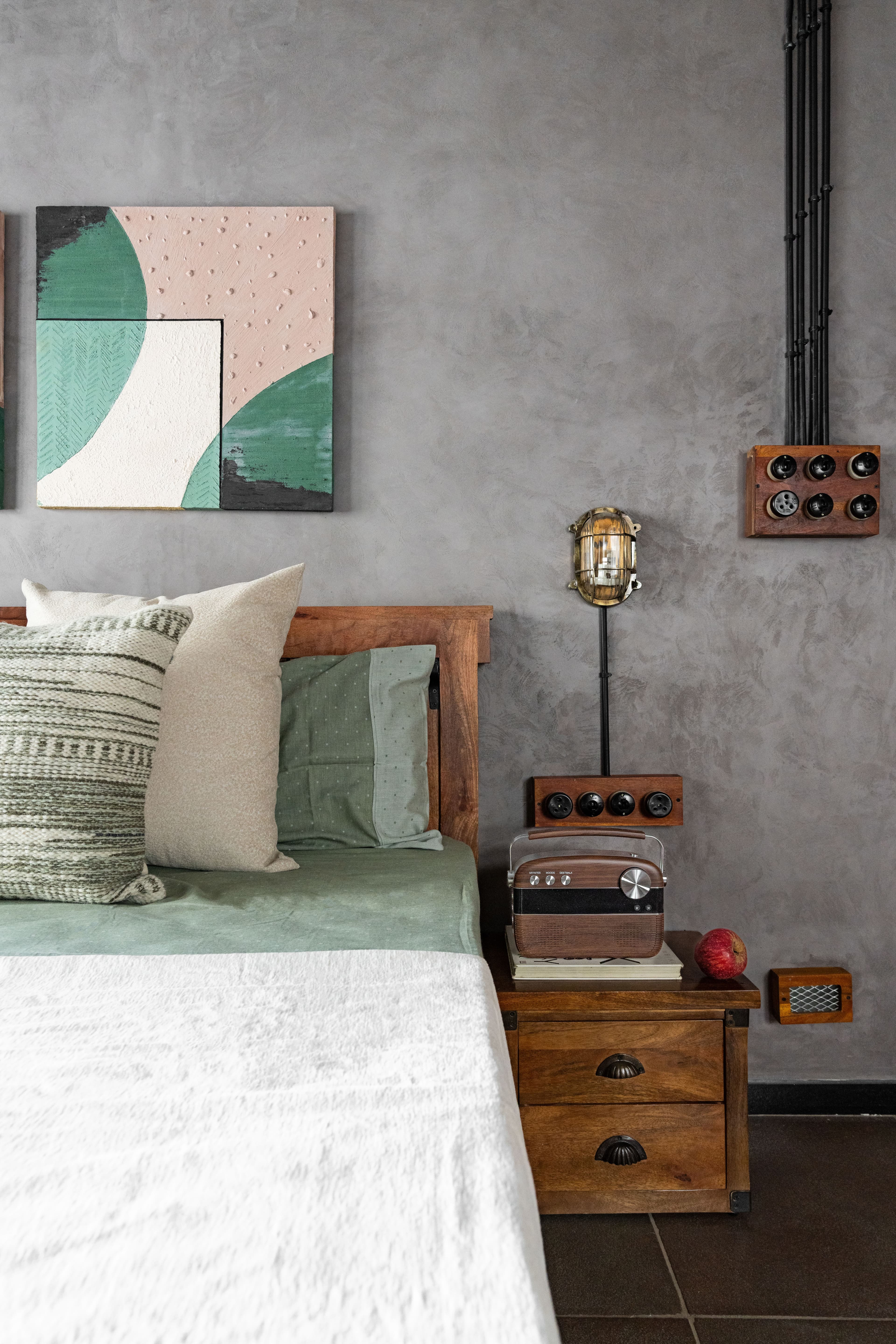 Second bedroom: sage and blush bedding beneath the artwork that permits them, a radio and one red apple.
