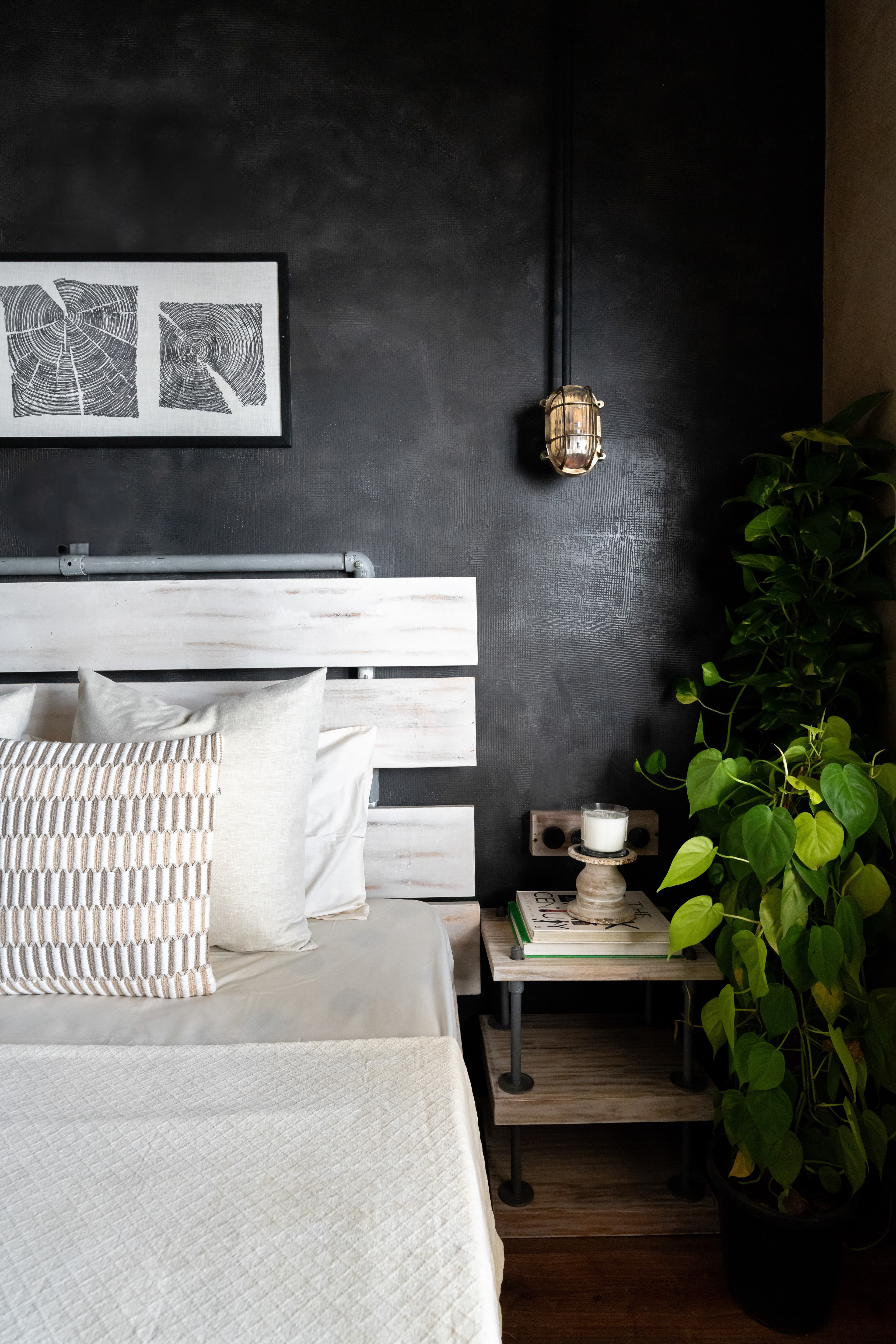 Bedside detail: candle on a stack of books beside the plank headboard.