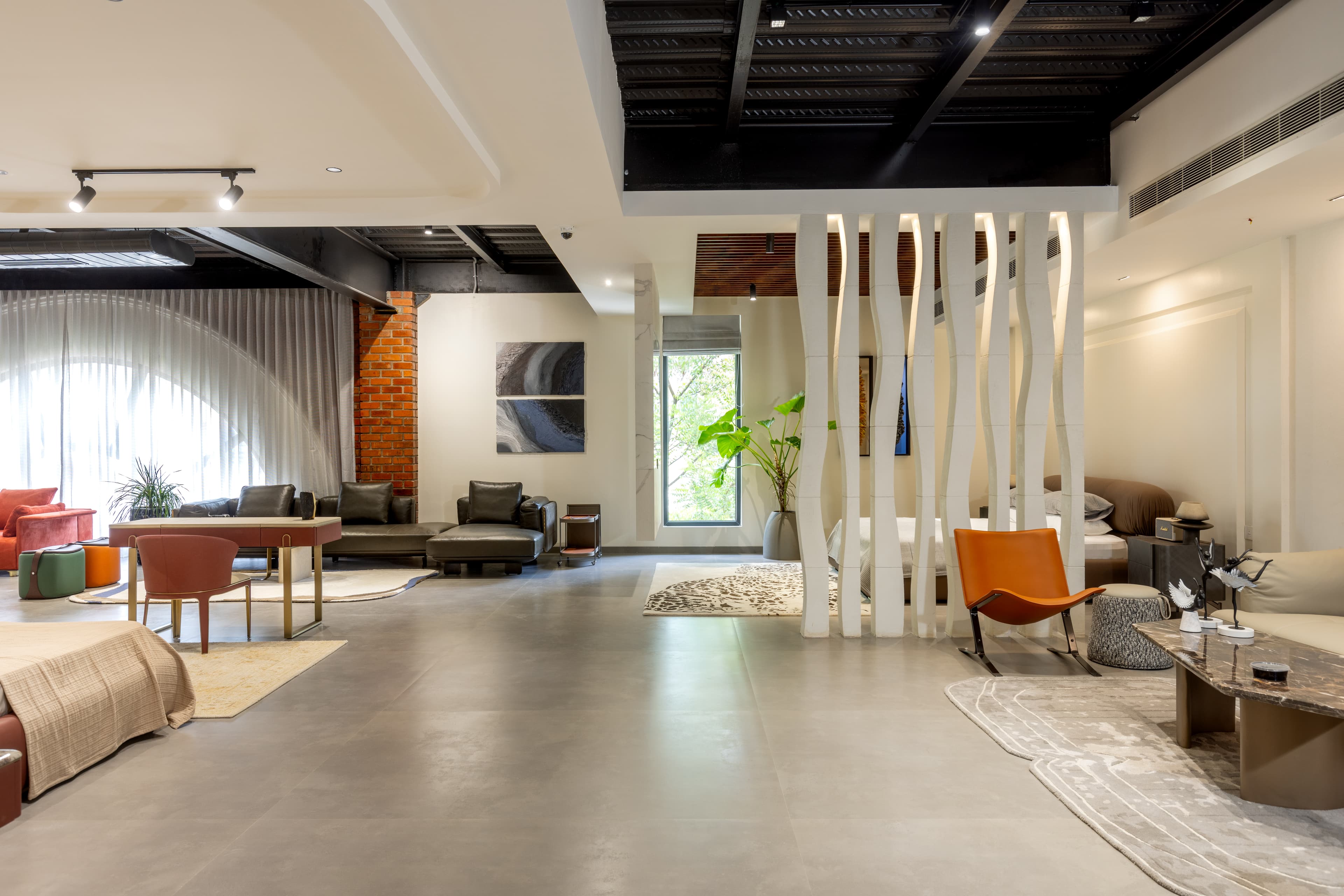 Lounge zone divided by a white sculpted partition beneath a dark ceiling.