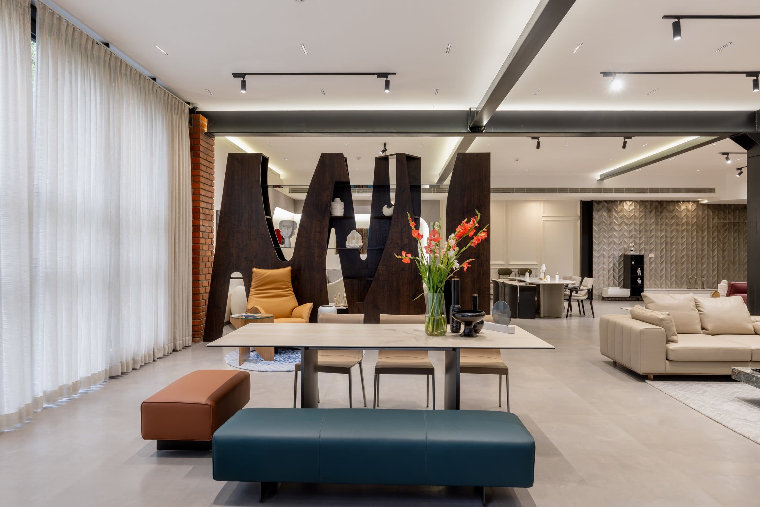 Tall sculptural shelf and a dining table set with dark vessels and gladioli.