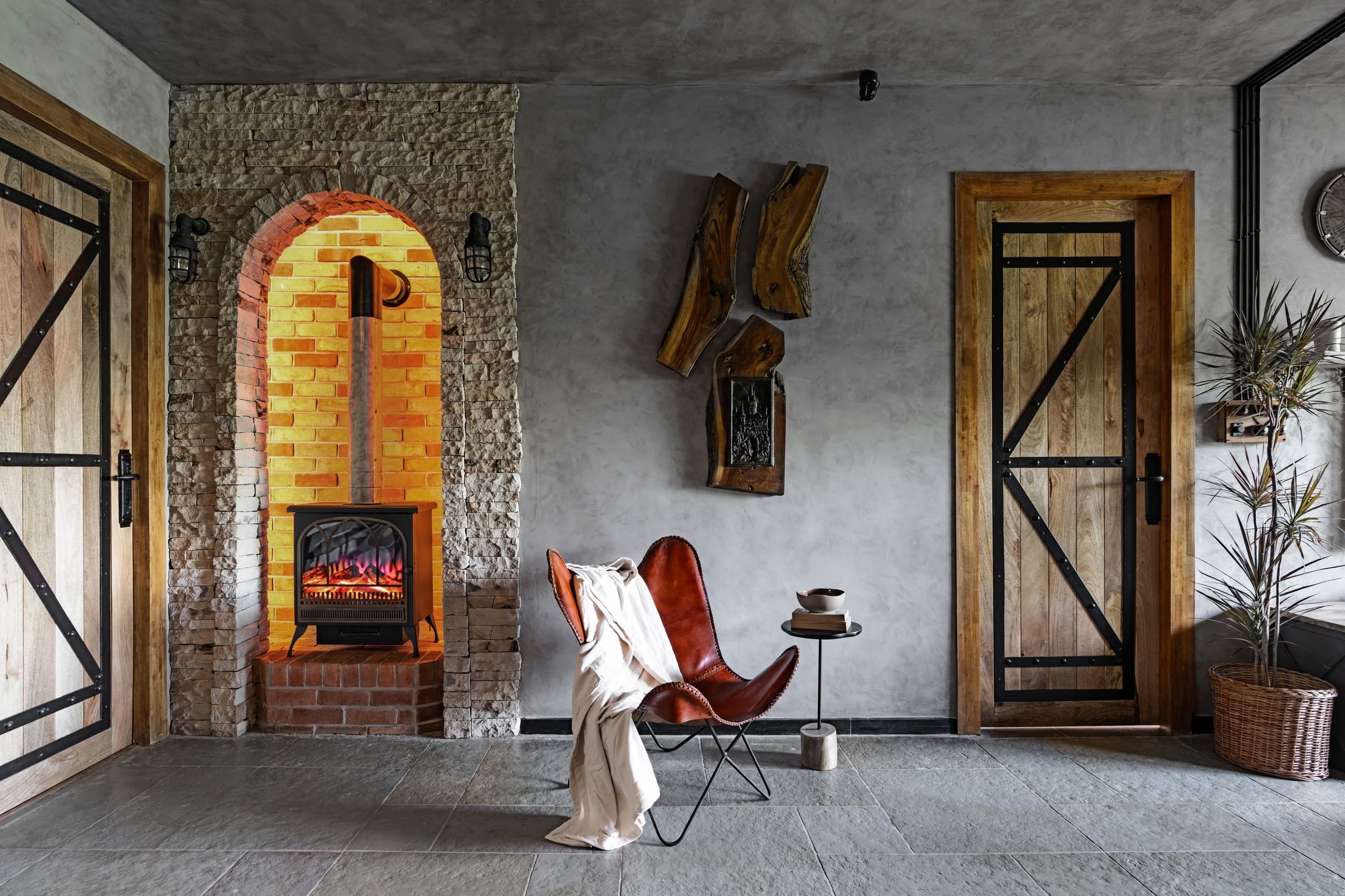 Fireplace nook: a leather butterfly chair with a cream throw beside the arched hearth.