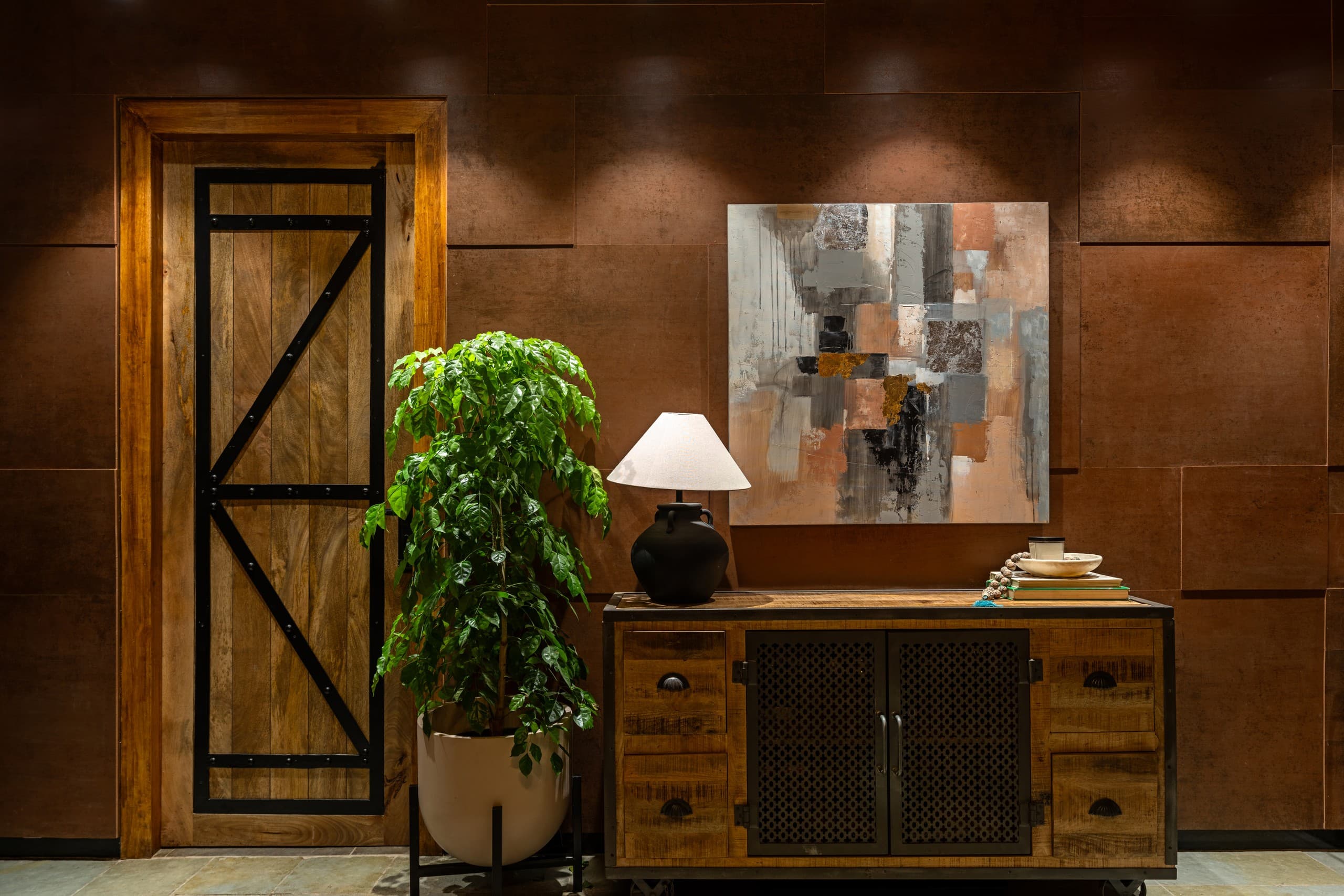 Timber console beneath a painting carrying the copper wall's own colours.
