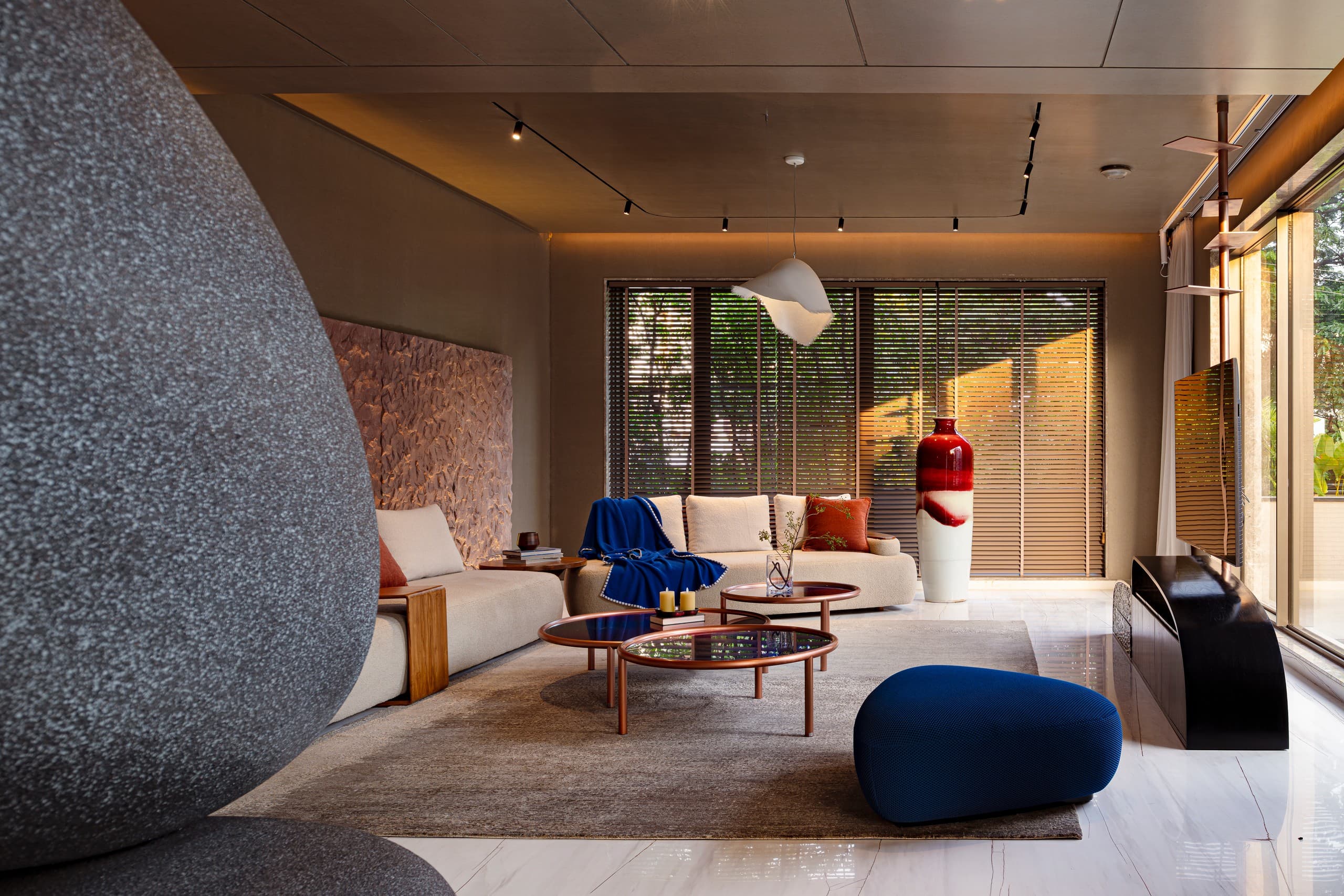 Sunlit lounge: ivory seating, cobalt throw and stool, nesting tables with coloured glass.