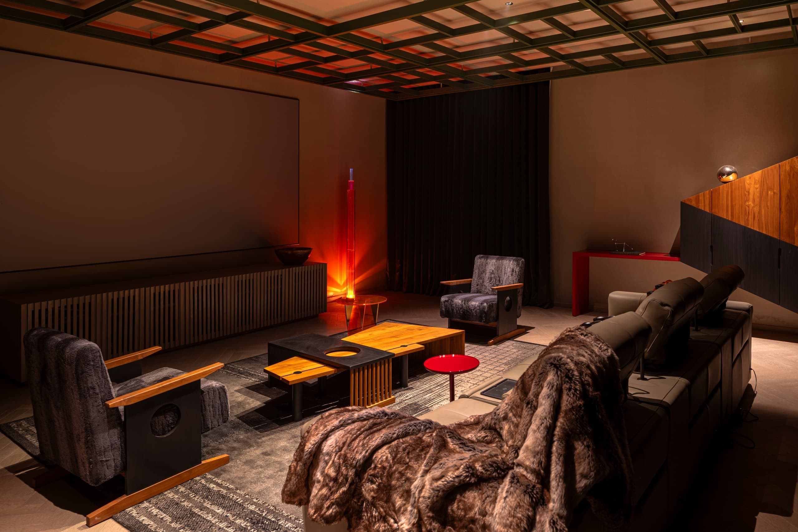 The den: fur throw, interlocked timber tables, a column of amber light.